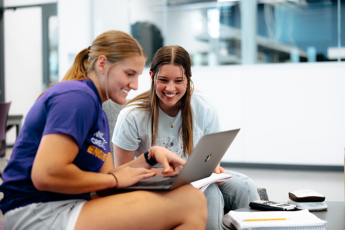 Two students looking at a laptop